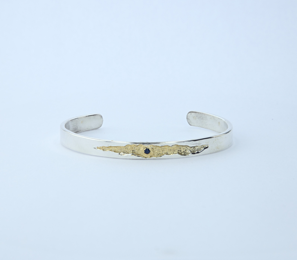 Bracelet jonc en argent massif, fêlure dorée sertie d'un saphir. Pièce unique inspirée de la lumière qui passe par la fêlure. Fait main en Ardèche.