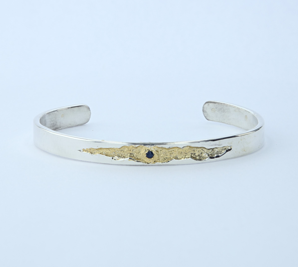Bracelet jonc en argent massif, fêlure dorée sertie d'un saphir. Pièce unique inspirée de la lumière qui passe par la fêlure. Fait main en Ardèche.