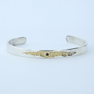 Bracelet jonc en argent massif, fêlure dorée sertie d'un saphir. Pièce unique inspirée de la lumière qui passe par la fêlure. Fait main en Ardèche.